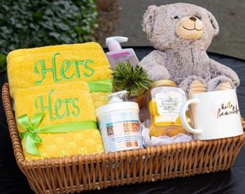 A gift basket with a yellow personalized towel, teddy bear, and bath and body spa items. Boston, Massachusetts