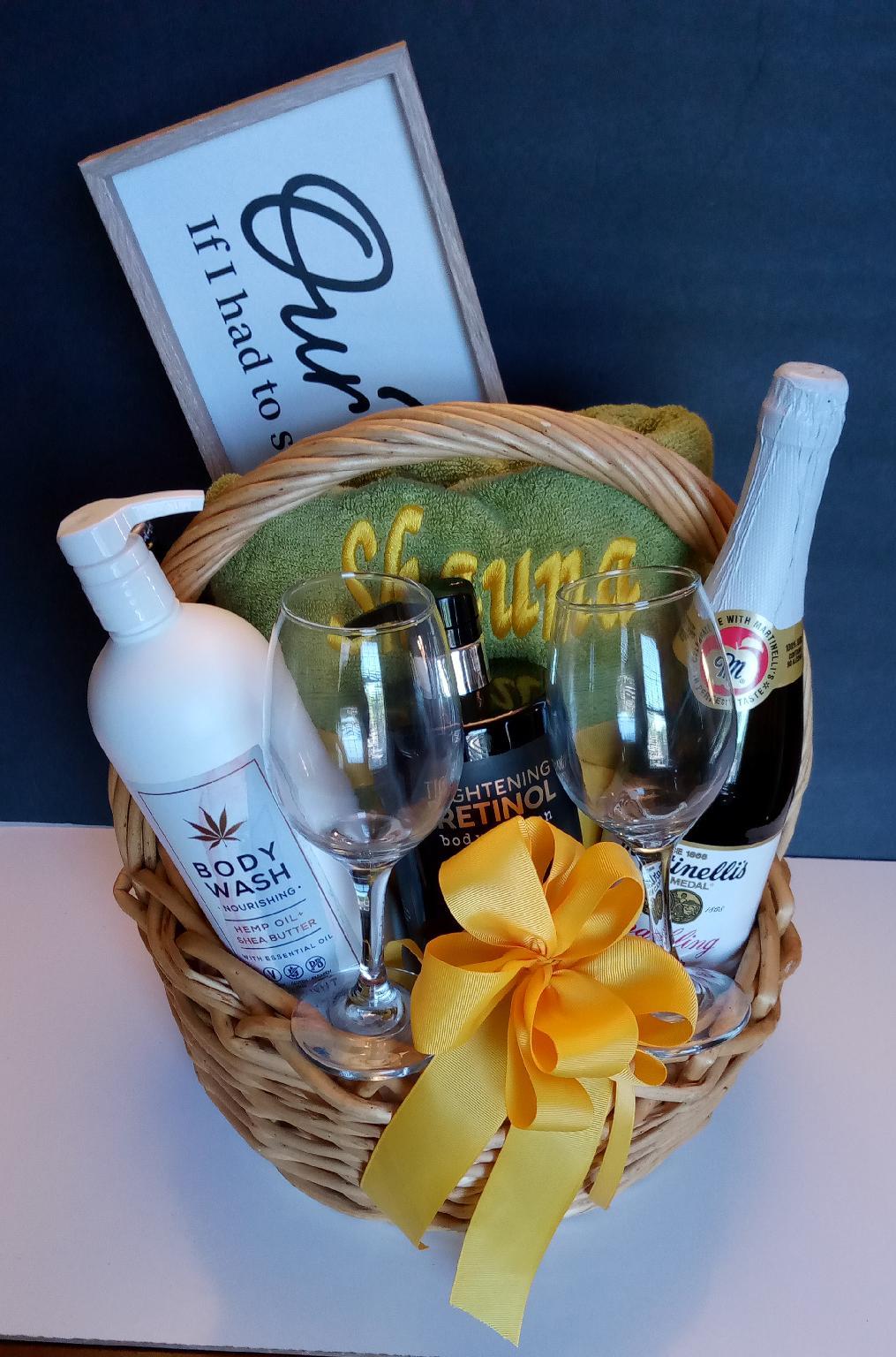 A gift basket for her to celebrate, champagne glasses, personalized bath towel, bath & body works.