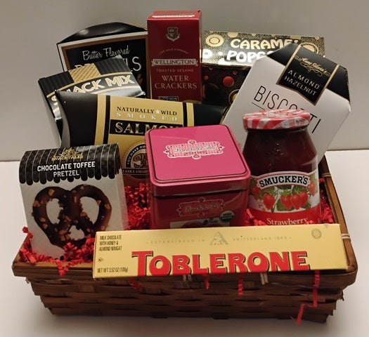 Gift basket with snacks and candies including Toblerone, Smucker's jelly, and pretzels.