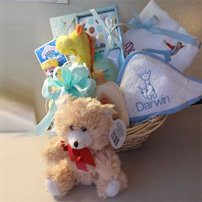 A baby boy gift basket in blue, packed with hooded towel, stuff animals, and baby body products