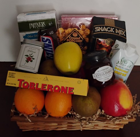 Chocolate gift baskets with assorted snacks and fruits, including caramel popcorn, candy bar, a jar of raspberry jam, oranges, apples, and pears.