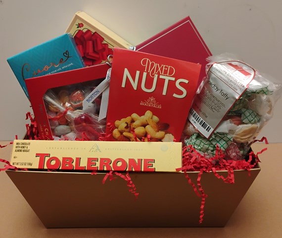 Gift basket with locally made chocolate, mixed nuts, and other snacks on a neutral background