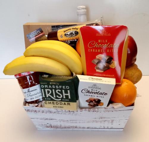 White gift box with bananas, apples, oranges, Irish cheddar, raspberry preserves, and chocolate caramel bites