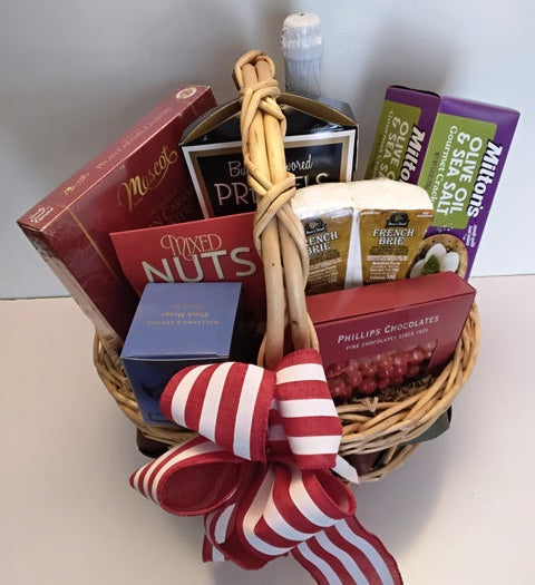 A wicker basket filled with Olive and herb gourmet crackers, mixed nuts, gourmet cluster pecan chocolates, chocolate coffee beans, butter flavor pretzels, cheese, and gourmet green tea. 