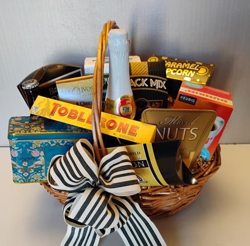 Handled wicker gift basket with sparkling cider, caramel popcorn, mixed nuts, chocolate and coffee pods, tied with a striped bow