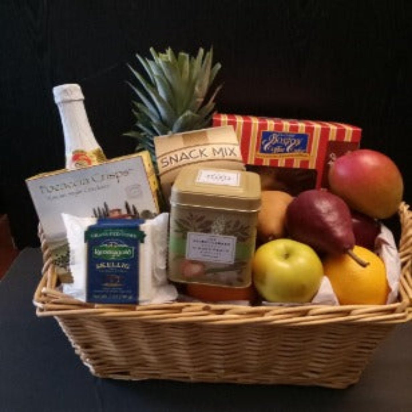 pineapple, red pears, apples, fresh pastry, and tea in this gift basket for delivery