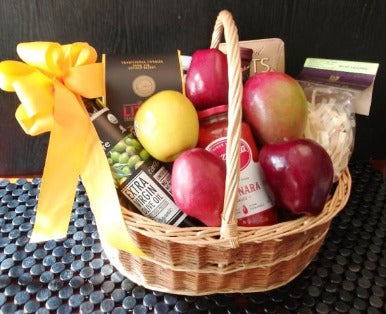 A basket packed with olive oil, pasta, aged cheese, sauce, nuts, and fruits. This gift basket is ideal for a housewarming delivery.